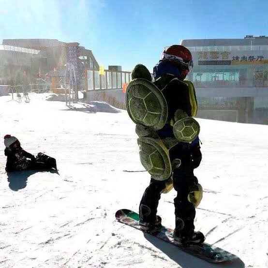 A well-padded rider in full protective gear on a snowboard